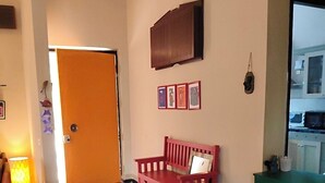 Un pasillo con un banco rojo, una mesa verde y una puerta que da a una habitación.