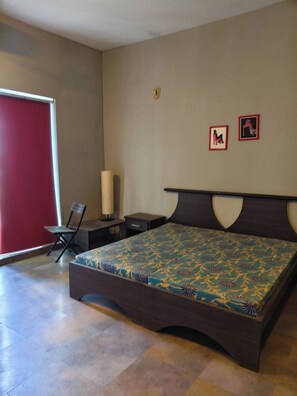 A bedroom with a large bed, a chair, a nightstand, and a red door.