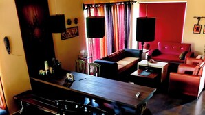 Un comedor con una mesa larga, varias sillas, un sofá y un sofá rojo.