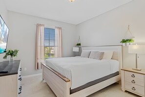 Quarto com cama, mesa de cabeceira, abajur e janela com persianas.