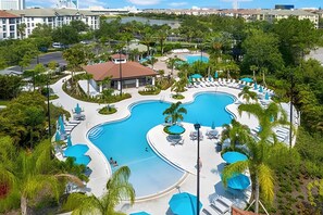 Resort com várias piscinas, áreas de descanso e vegetação exuberante.