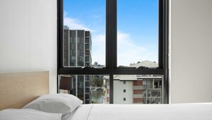 A hotel room with a large window, a bed, and a view of buildings and a river. - Spaciously Bright 1-bed Apartment (Brisbane)