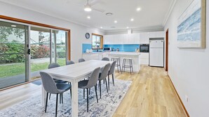 A modern kitchen with white cabinets, a blue backsplash, and a built-in oven. - 4-bed Beach House With Garden & Alfresco Dining (Tomakin)
