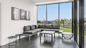 A modern living room with a sectional sofa, a coffee table, and a small round table. There are three framed artworks on the wall. - Contemporary 1-bed in the Heart of St Kilda (Melbourne)