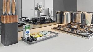 A modern kitchen with a gas stove, stainless steel appliances, and a tray with milk cartons and condiments. - Modern 1-bed Apartment Close to Attractions (Melbourne)