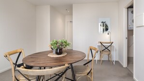 Un coin repas avec une table ronde en bois, quatre chaises en osier et une plante en pot.