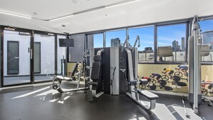 A modern gym with exercise equipment, large windows, and a city view. - Chic 1-bed With Harbour Views & Pool by Tram Line (Melbourne)