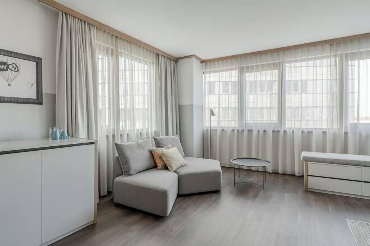 A modern living room with a grey sofa, a round coffee table, and a white cabinet.