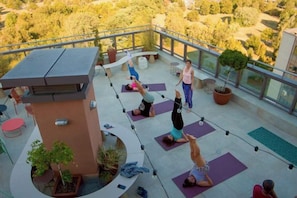 A rooftop yoga class with participants on mats, surrounded by potted plants and outdoor furniture. - WN Hotel (Sofia)