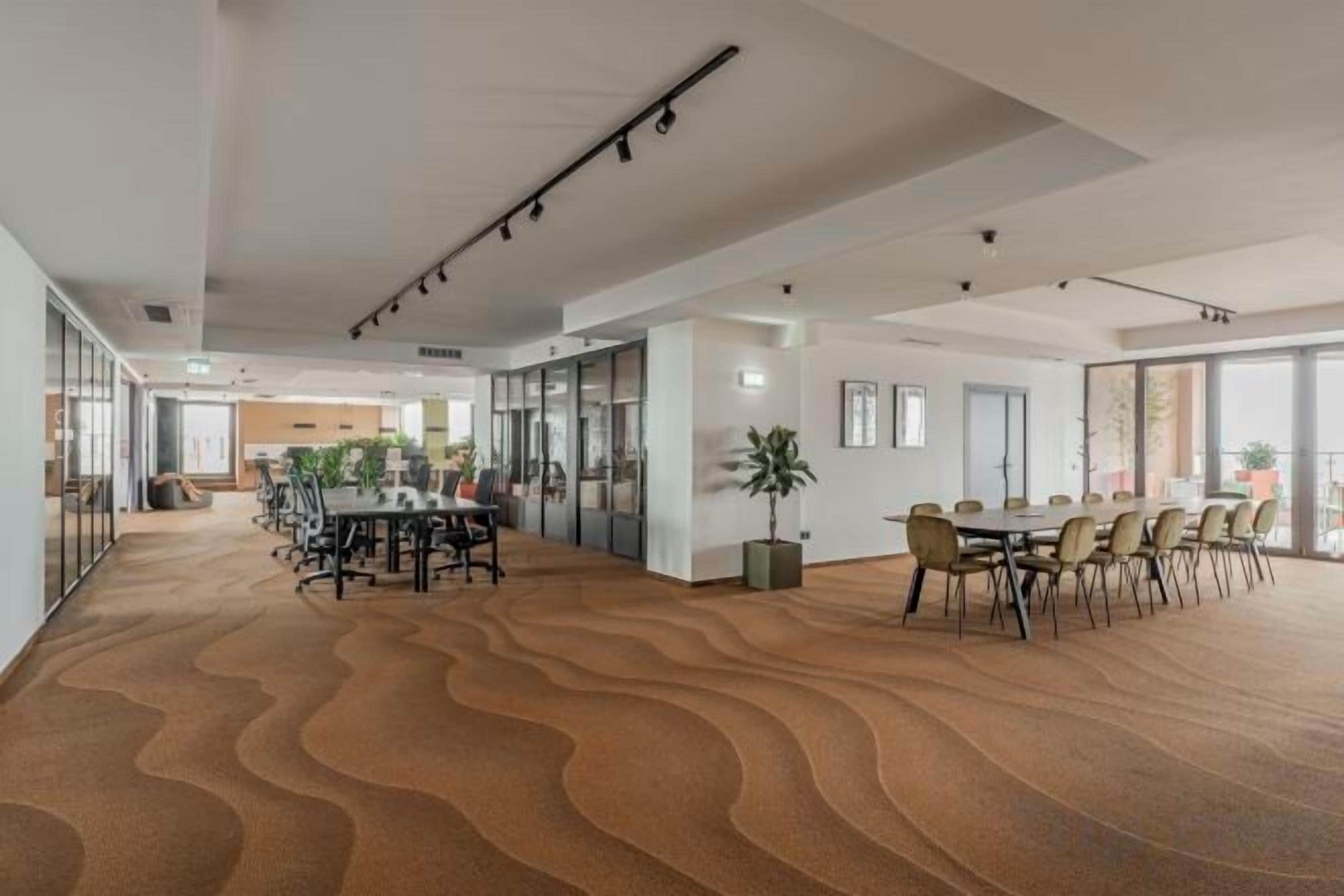 Una amplia sala de conferencias con alfombra ondulada, divisiones de vidrio y un diseño moderno del techo.
