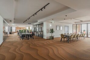 Tilava kokoushuone, jossa on aaltoileva matto, lasiseinät ja moderni kattorakenne.