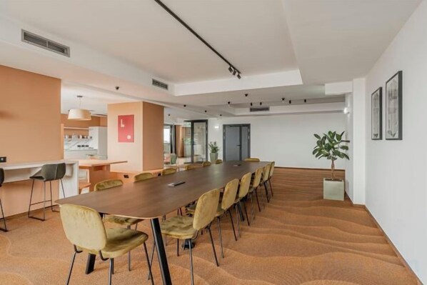 Una sala conferenze con un lungo tavolo, sedie e un vaso di fiori.