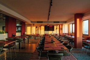 A conference room with multiple tables and chairs, large windows, and a modern interior design. - WN Hotel (Sofia)