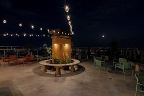 An outdoor seating area with chairs and tables, a central decorative structure, and string lights. - WN Hotel (Sofia)