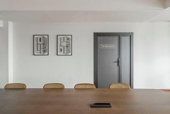 A conference room with a long table, four chairs, and two framed abstract artworks on the wall. - WN Hotel (Sofia)