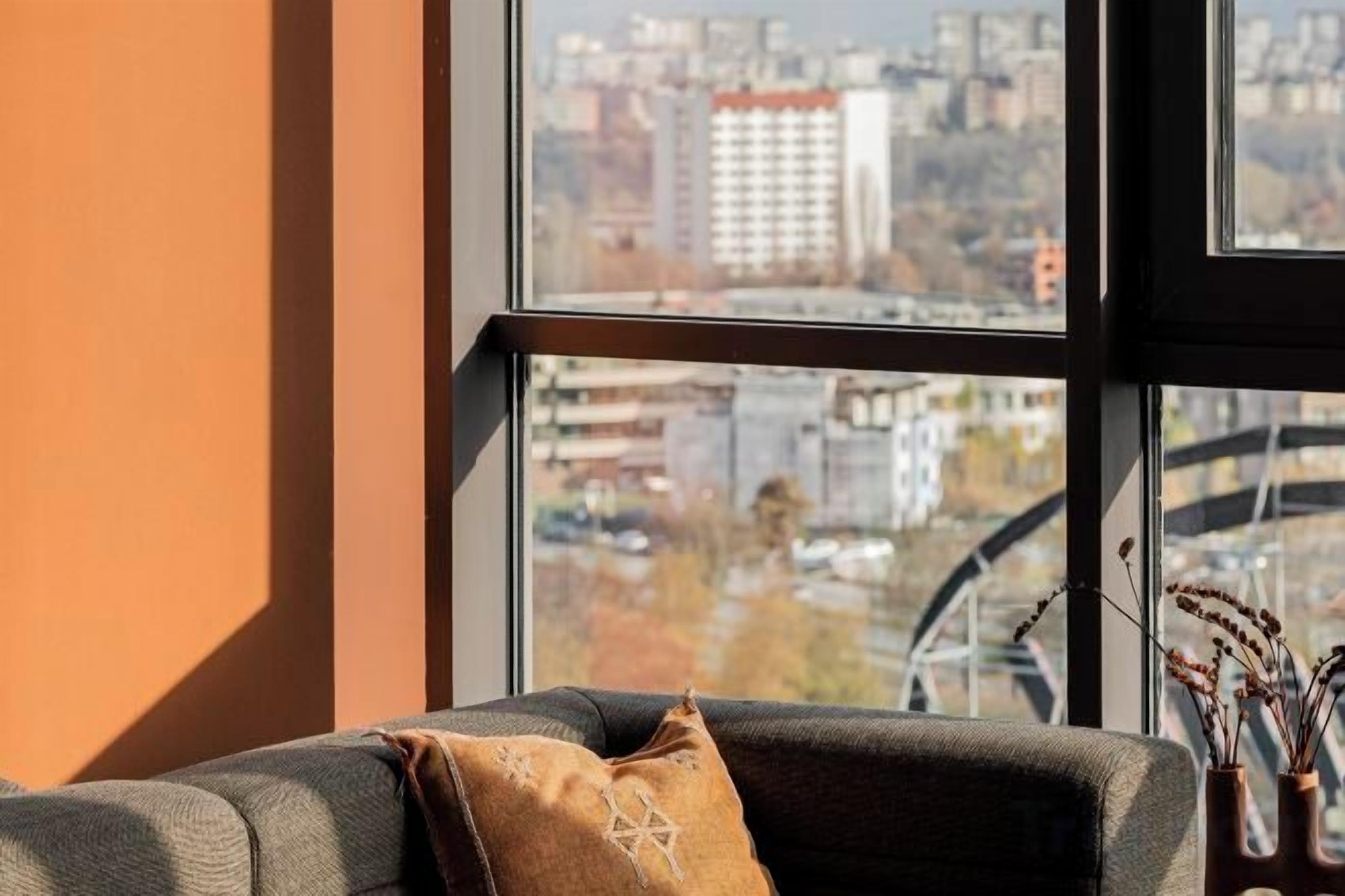 A room with a sofa and a window overlooking a cityscape.