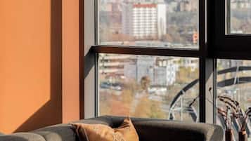 A room with a sofa and a window overlooking a cityscape.