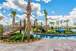 A pool area with a palm tree, a wooden staircase, and a clear blue sky.