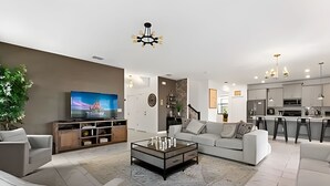 Een moderne woonkamer met een flatscreen televisie, een glazen salontafel en een bank.