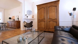 A living room with a glass coffee table, a black leather sofa, a wooden wardrobe, and a dining area with a table and chairs. - Villa centrale Douai | 5 ch et terrasse (Douai)