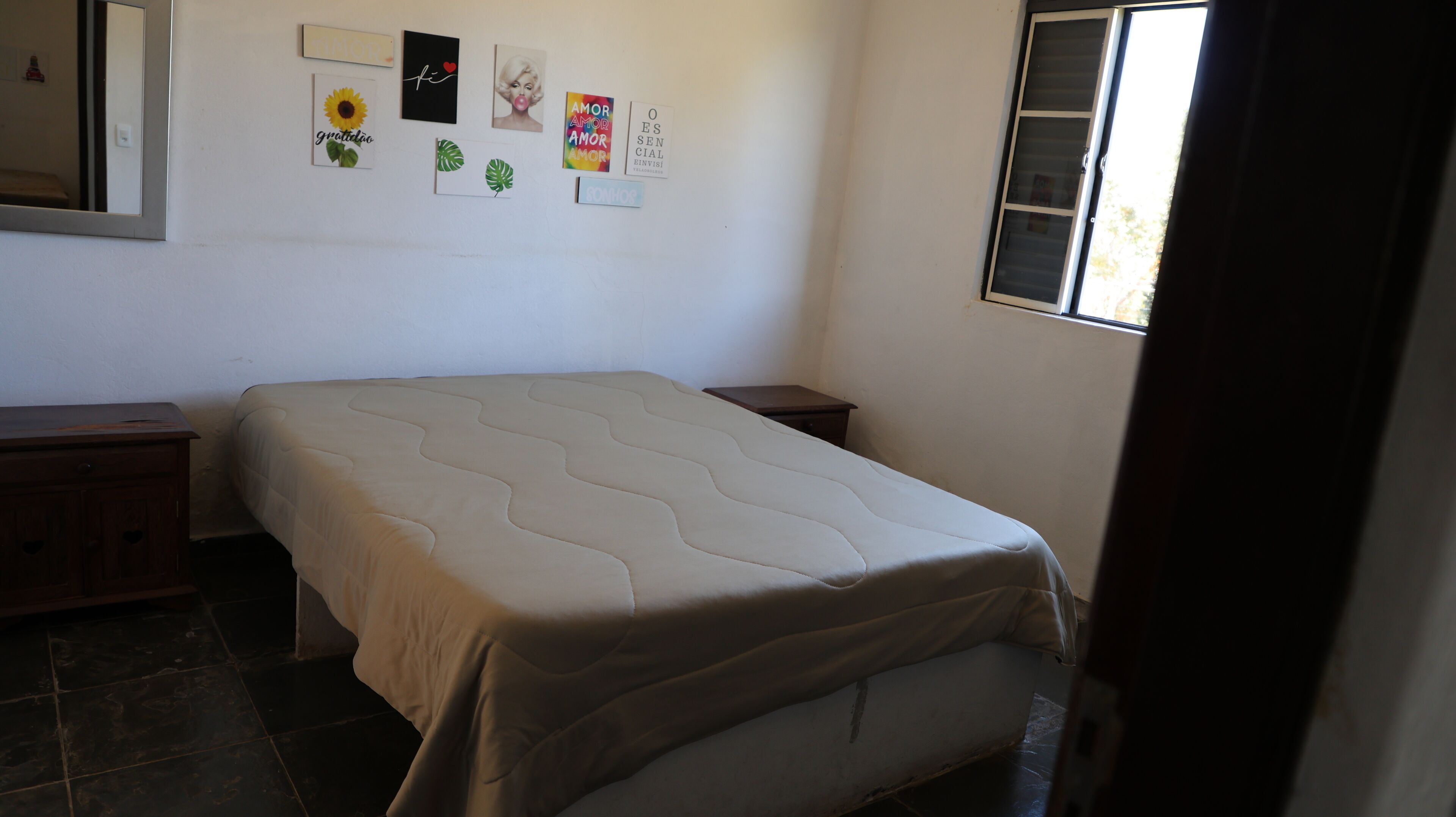 Une chambre à coucher avec un lit, une table de chevet, une commode et une fenêtre.
