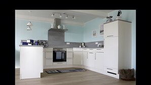 A modern kitchen with white cabinetry, a built-in oven, and pendant lighting.