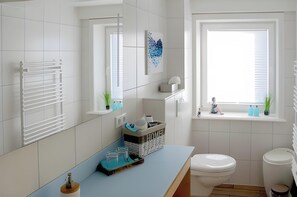 Une salle de bain moderne équipée de toilettes, d’un bidet et d’une fenêtre donnant sur un beau paysage.