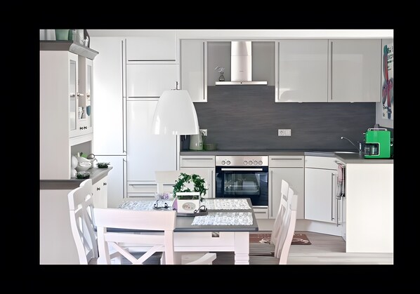 A modern kitchen with white cabinetry, a central island, a built-in oven, and a microwave.