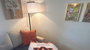 Un salon avec un canapé, une lampe et une couverture ornée du logo de l’université d’Auburn.