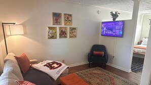 A living room with a sofa, ottoman, and a television mounted on the wall.