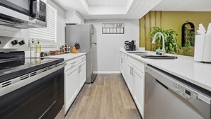 A modern kitchen with a coffee bar, stainless steel appliances, and a wooden floor.