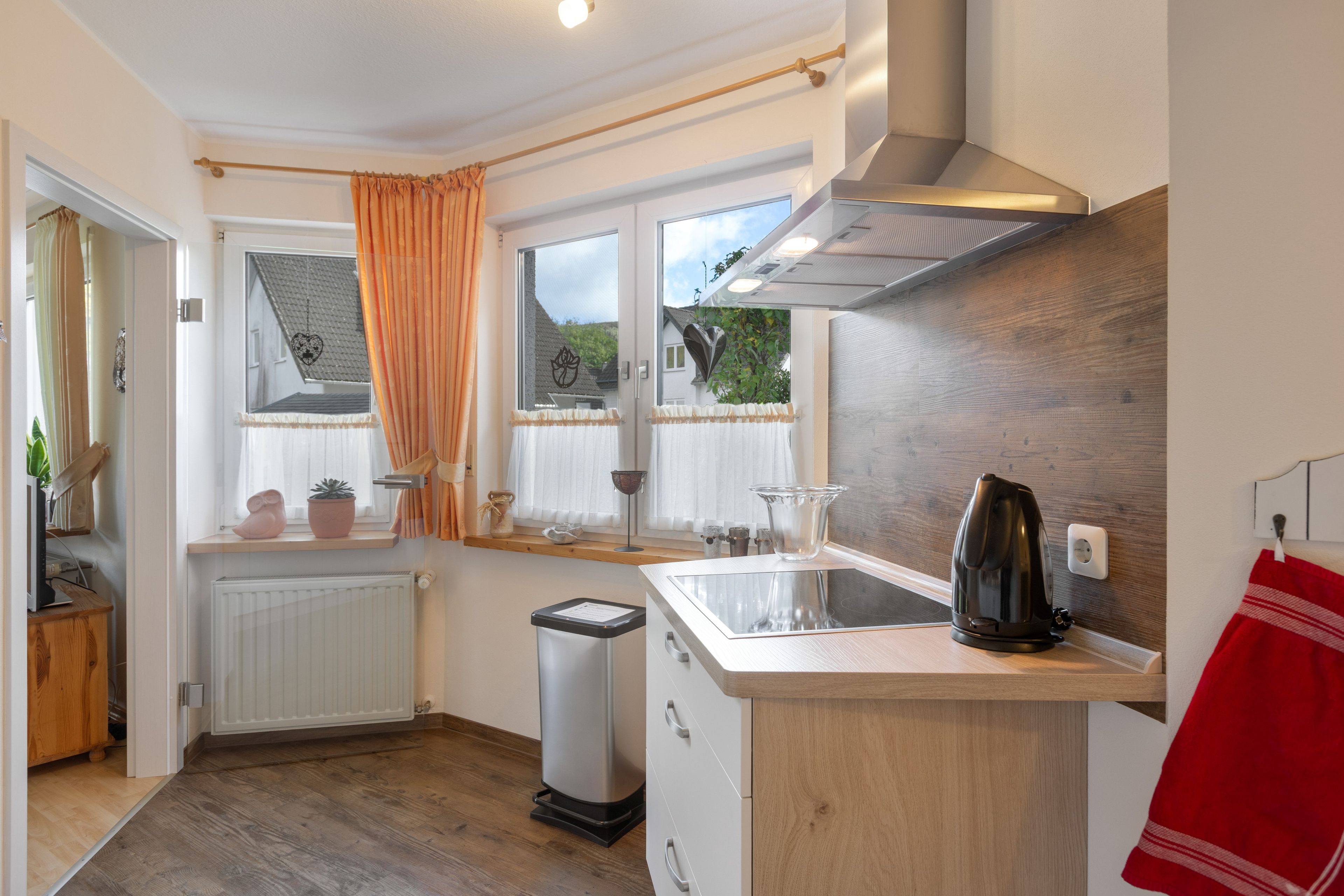 A compact kitchen with a wooden countertop, a kettle, and a trash bin.