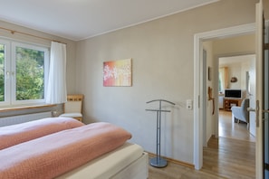 Une chambre à coucher avec un lit, une lampe sur pied et un tableau accroché au mur.