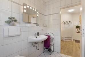 Une salle de bain moderne avec un lavabo blanc, un miroir et une plante en pot.