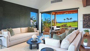 Una sala de estar moderna con un ventanal que ofrece vistas a un campo de golf y al océano.