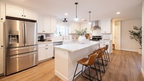 A modern kitchen with stainless steel appliances, white cabinetry, and a central island with bar stools. - Arcadia Oasis | Heated Pool & Near Old Town (Phoenix)