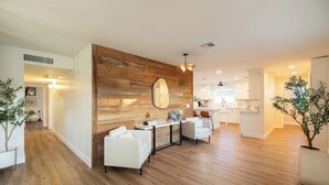 A spacious living area with a wooden accent wall, a dining table with chairs, and a kitchen in the background. - Arcadia Oasis | Heated Pool & Near Old Town (Phoenix)