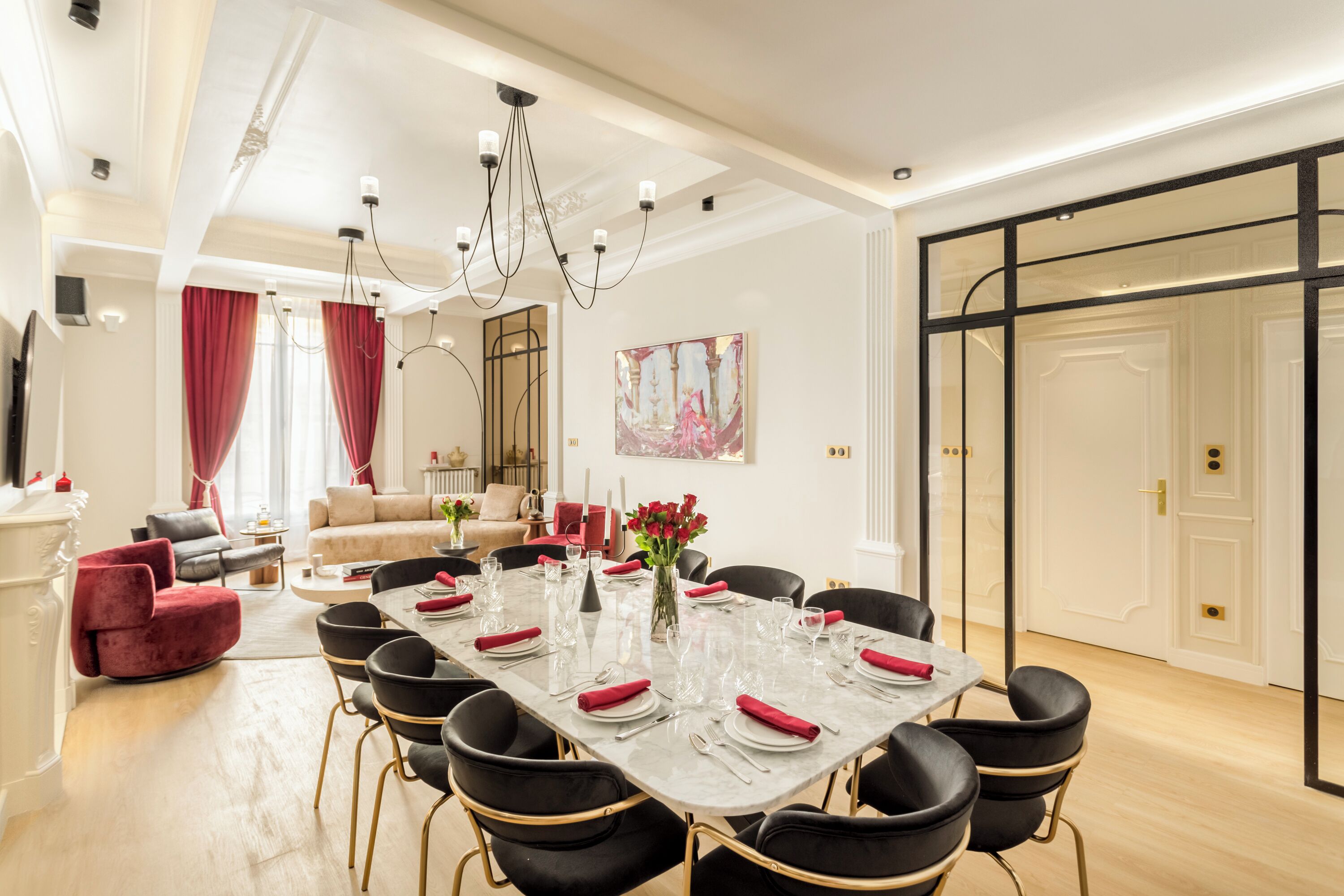 A dining area with a marble table set for six, surrounded by black chairs with gold legs.