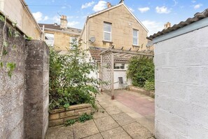 Ein Garten mit Gartenmöbeln, einer Pergola und einer weißen Mauer.