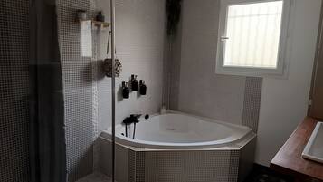 Une salle de bain moderne avec une baignoire sur pieds, un espace douche et une fenêtre laissant entrer la lumière naturelle.