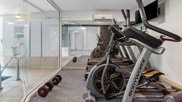 Une salle de sport équipée de tapis de course, d’un vélo d’appartement et d’haltères.
