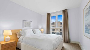 Une chambre d’hôtel avec un lit, une table de chevet, une lampe et une fenêtre avec des rideaux.