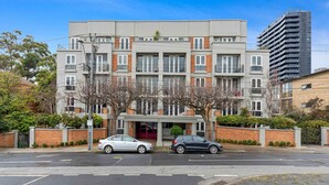 Un immeuble résidentiel à plusieurs étages, doté d’une façade en briques, de nombreux balcons et d’une entrée abritée.