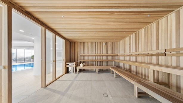 Ein modernes Interieur mit Holzwandverkleidung, einer langen Bank und einem kleinen Tisch mit einem Krug.
