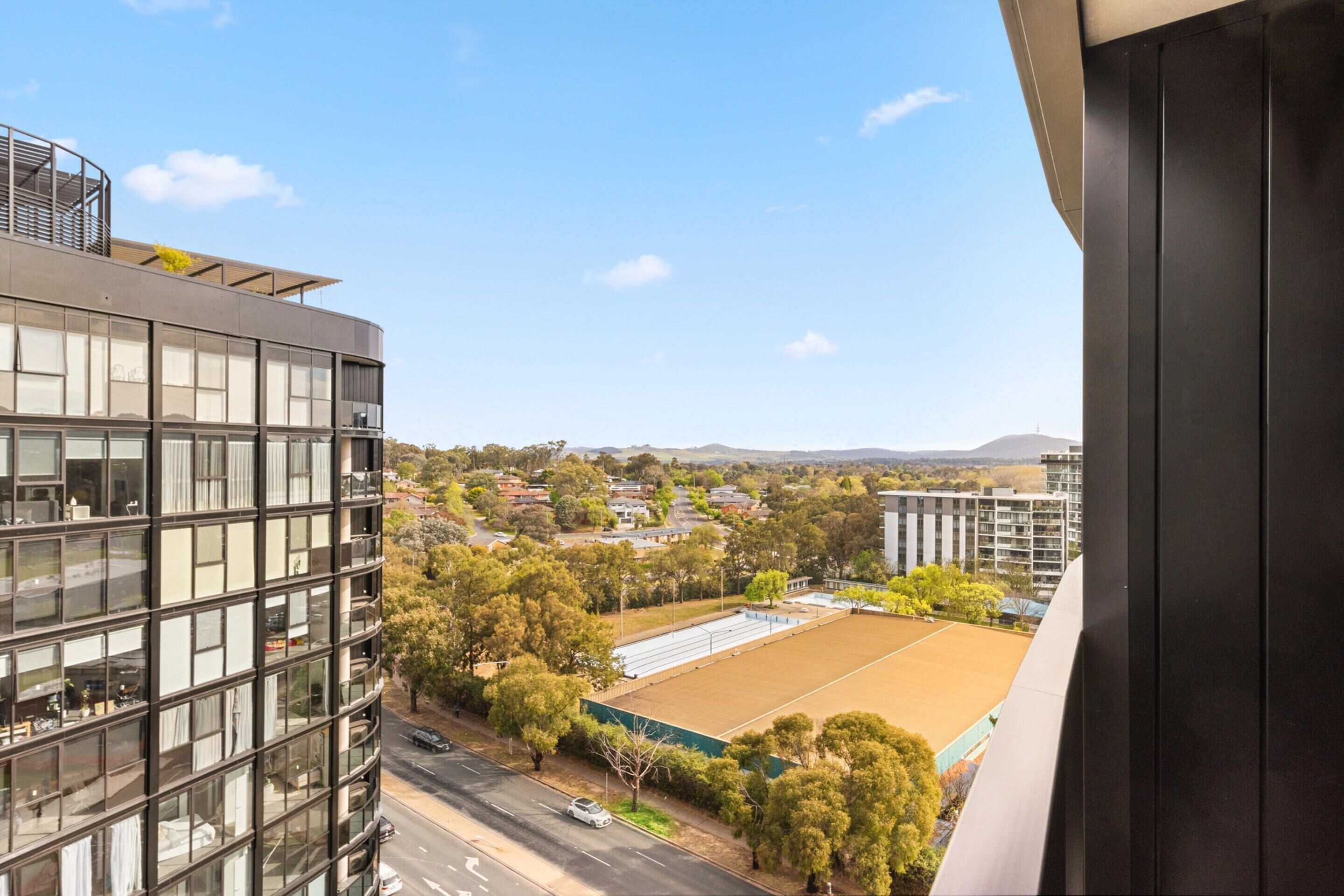 A modern building with large windows and a view of a sports field and surrounding area.