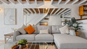 A modern living room with a grey sectional sofa, a glass coffee table, and a staircase leading to an upper level. - Chic 2-bed Cabin-style Home by Mooloolaba Beach (Sunshine Coast)