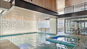 An indoor swimming pool with clear water, a wooden ceiling, and a glass wall. - Riverside 2-bed by Brisbane's Landmarks (Brisbane)