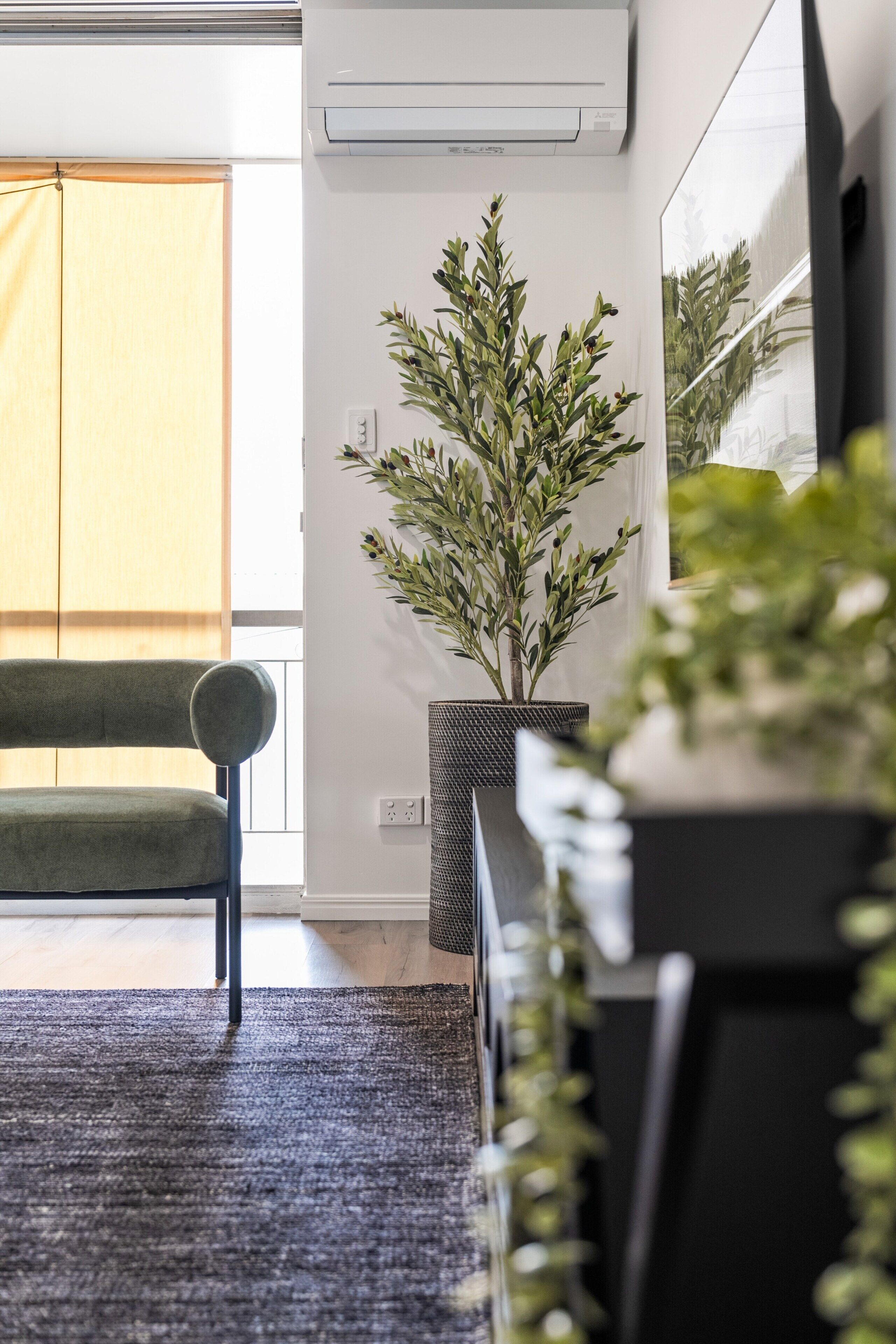 Een moderne woonkamer met een bank, een potplant en een groot raam.