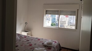 A bedroom with a bed, a window, and a wall-mounted air conditioner. - BOULEVARD APARTMENT (Rosario)