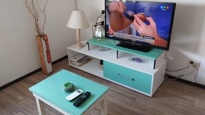 A living room with a television, a lamp, a coffee table, and a remote control. - BOULEVARD APARTMENT (Rosario)